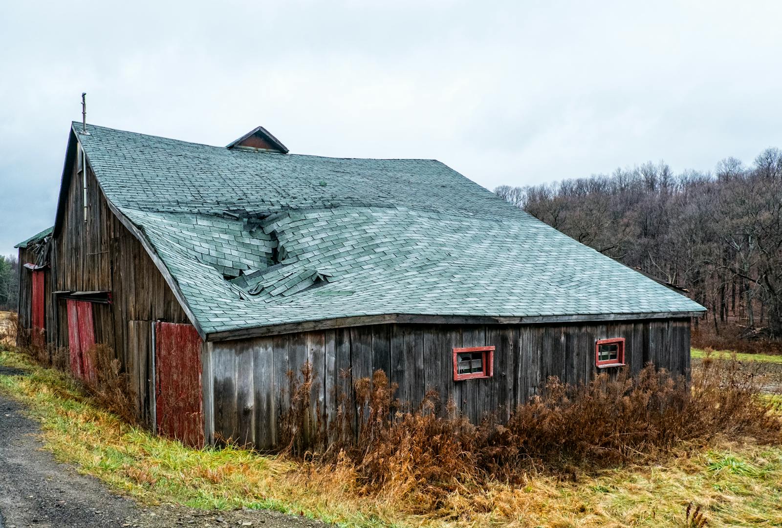 Wooden home with a partially collapsed shingle roof after a storm