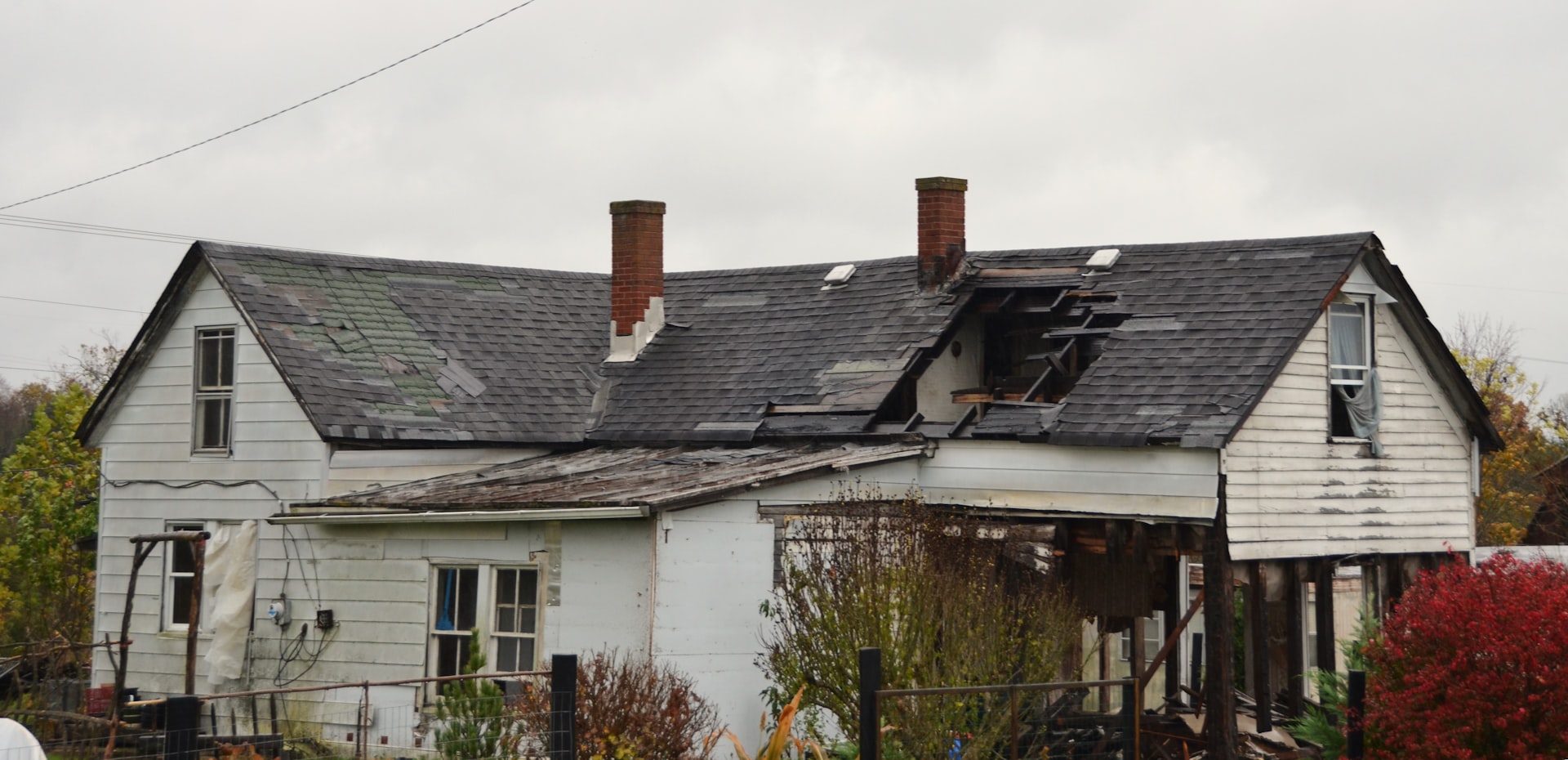Neglected, storm-damaged residential roof with missing and broken shingles